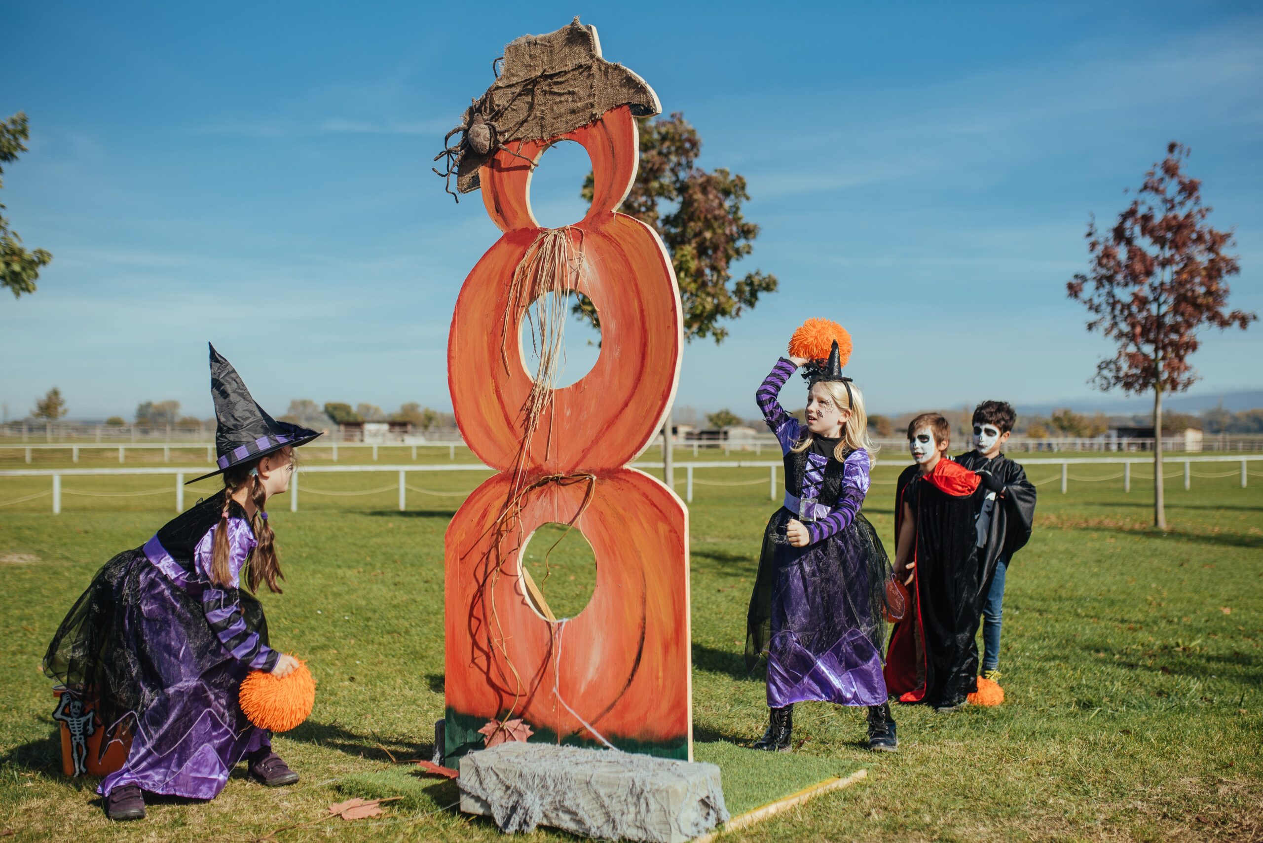 Verkleidete Kinder schmeißen Kürbisse durch eine große Kürbisfigur
