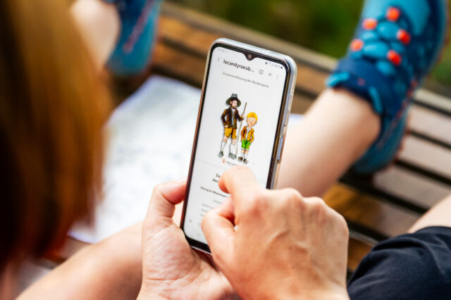 Eine Frau und ein Kind am Handy beim interaktiven Wanderweg