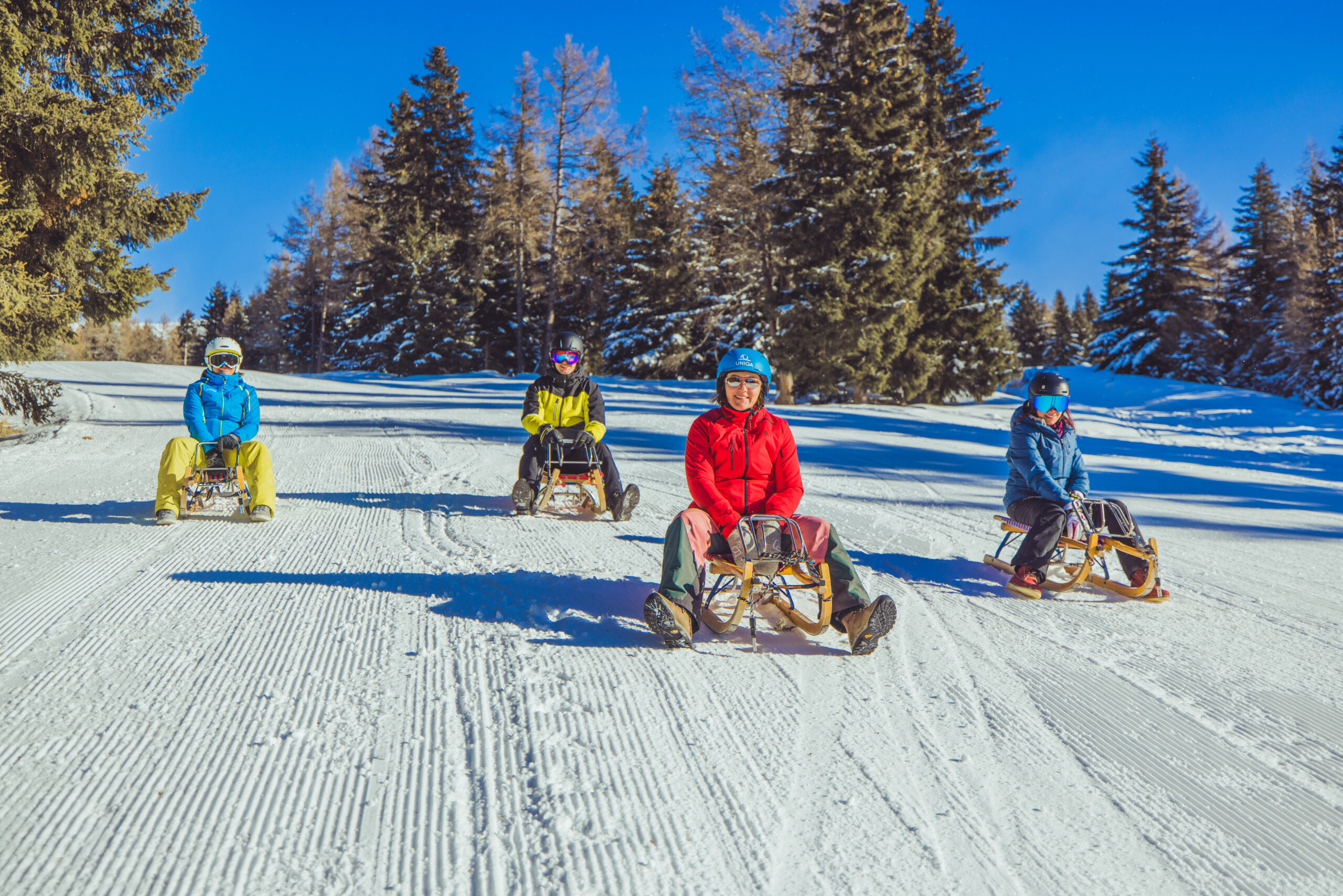 Familie rodelt die Piste runter.