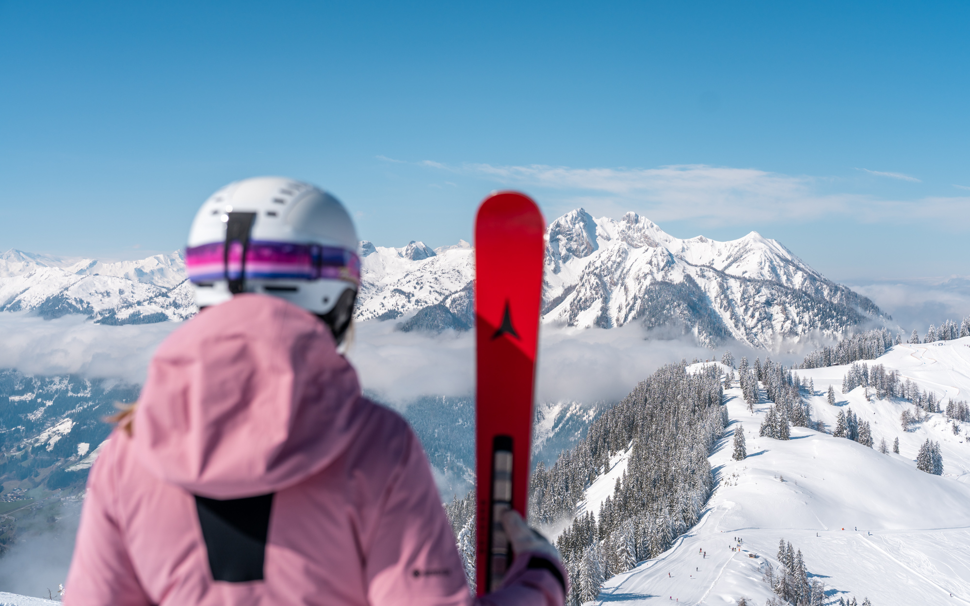 Person blickt auf die Piste und die schneebedeckten Gipfel.