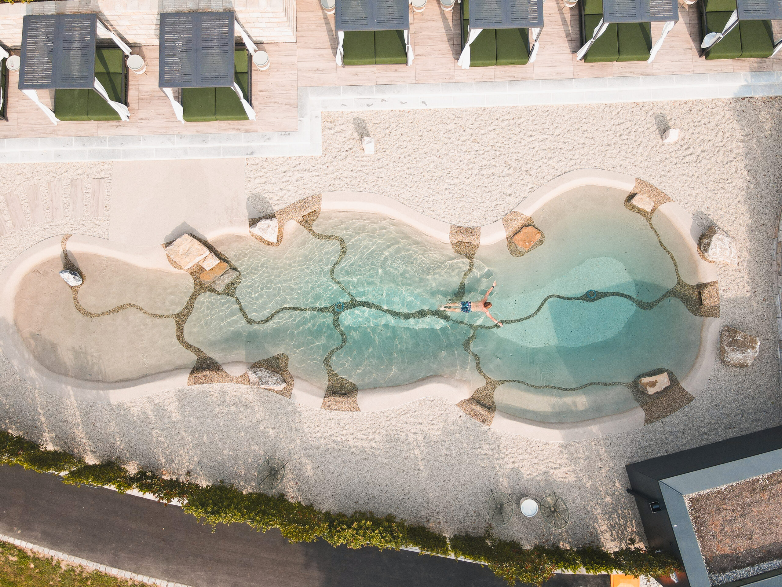 Person schwimmt durch Outdoorpool eines Hotels