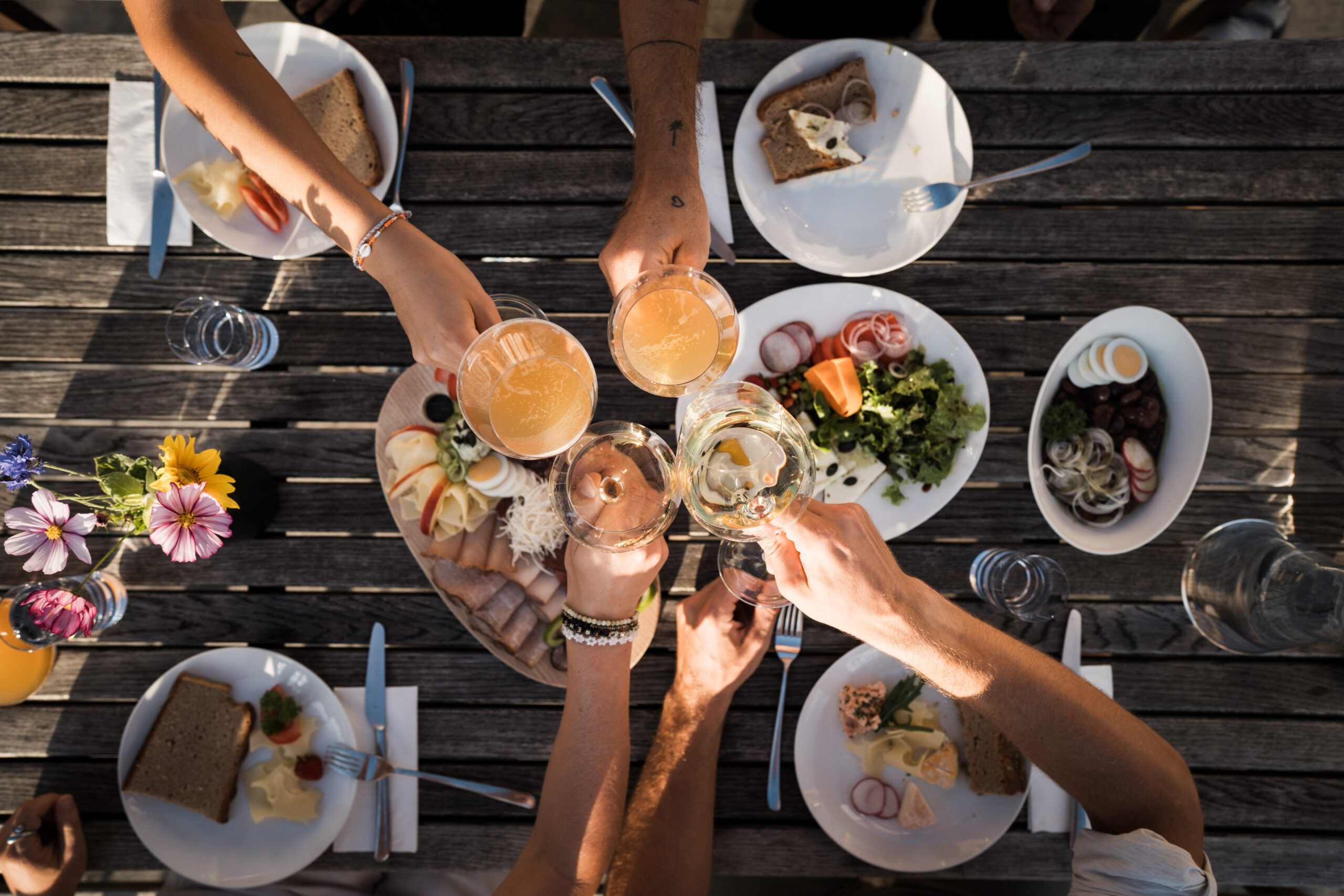 Menschen stoßen an über einem Tisch voll mit Essen