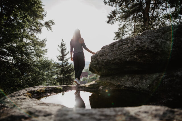 Eine Frau steht auf einem Granitfelsen und blickt in die Ferne