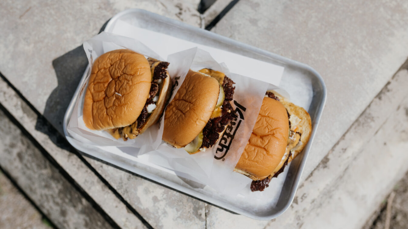 drei Smash Burger von Kvetch liegen auf einem Silbertablett in der Sonne