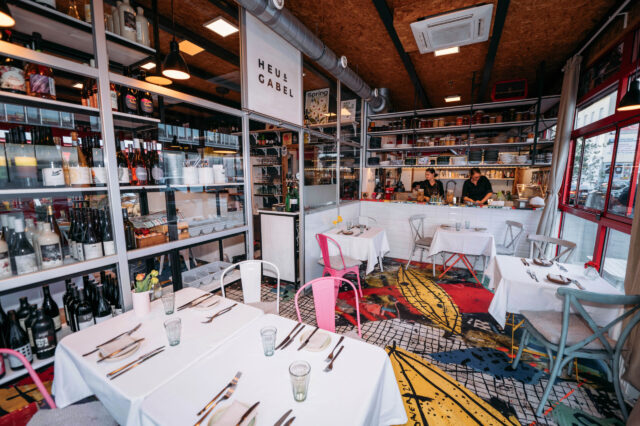 gedeckte Tisch, Regale gefüllt mit Weinflaschen und Blick in die Küche des Restaurants Heu und Gabel am Meidlinger Markt in Wien