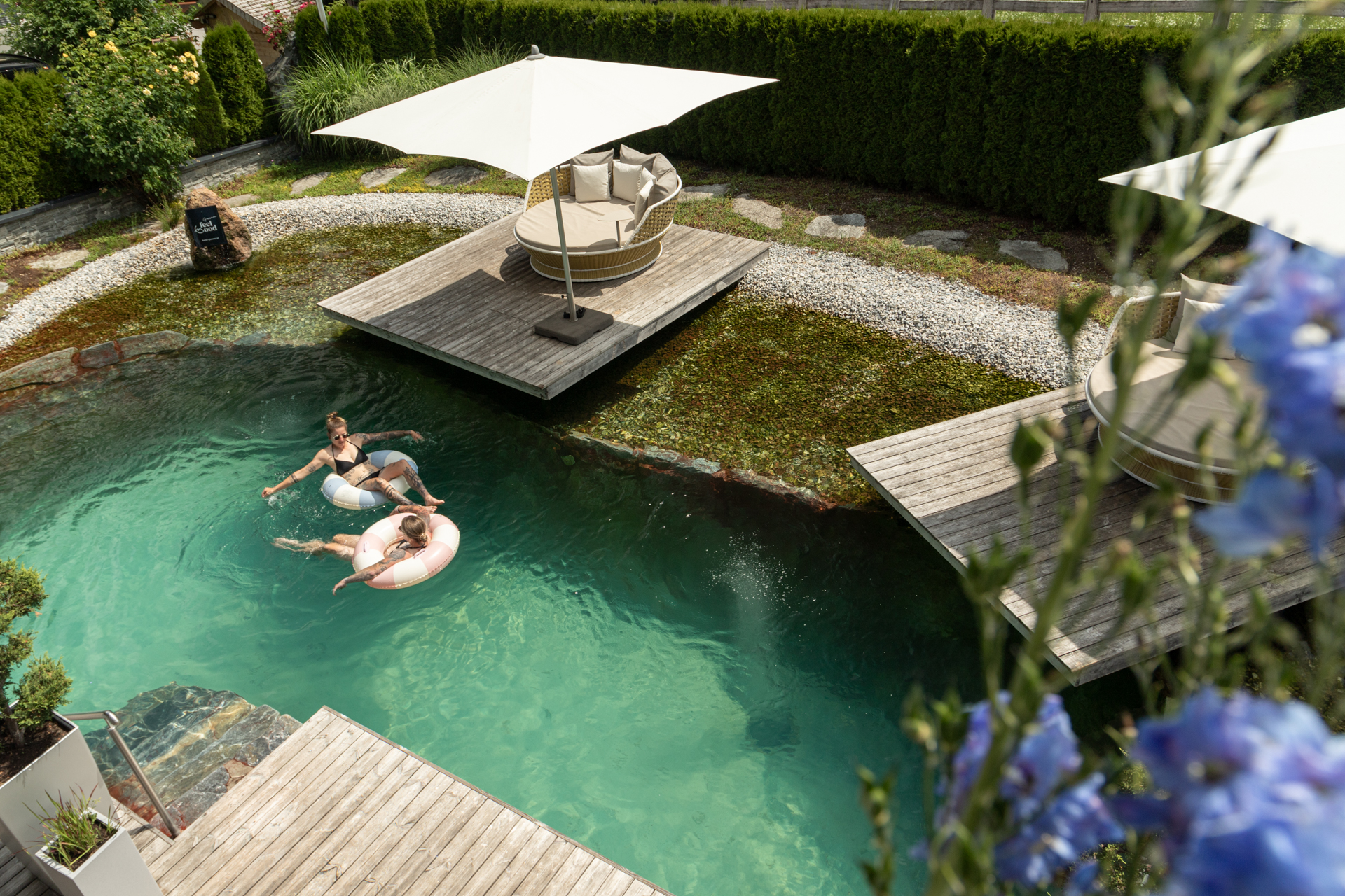 Zwei Personen treiben auf Luftmatratzen im Außenpool vom Hotel Gassner.
