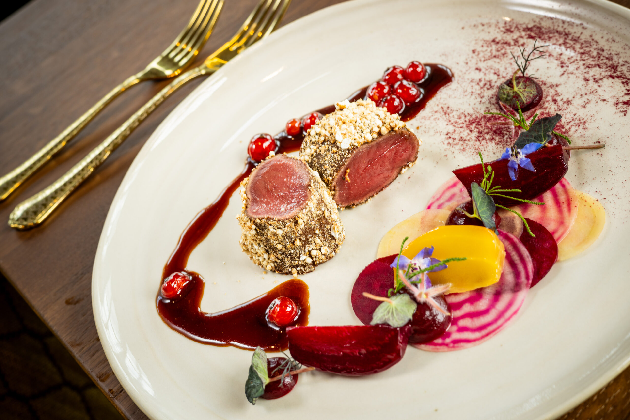 Ein bunter Teller im Restaurant vom Hotel Knappenhof, mit Rehrücken, Früchten und Sauce.