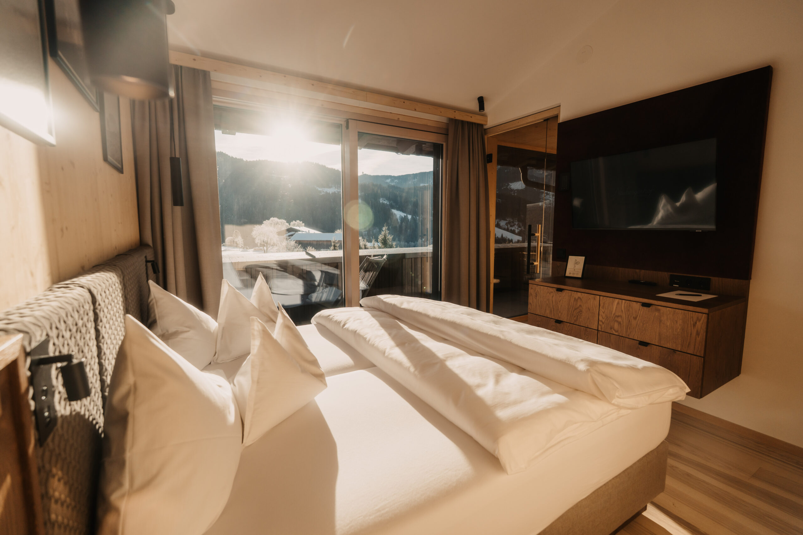 Blick auf das Schlafzimmer in der Top Suite im Hotel Neubergerhof mit Bett und Ausblick vom Balkon.