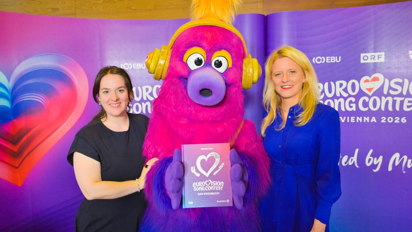 Eurovision Song Contest Kochbuch: Zum ESC in Wien 2026 bringen Brandstätter und ORF ein Buch mit Rezepten aus allen Teilnehmerländer heraus. Im Bild u.a.: Manuela Tiefnig (Autorin) und ESC-Maskottchen Auri.
