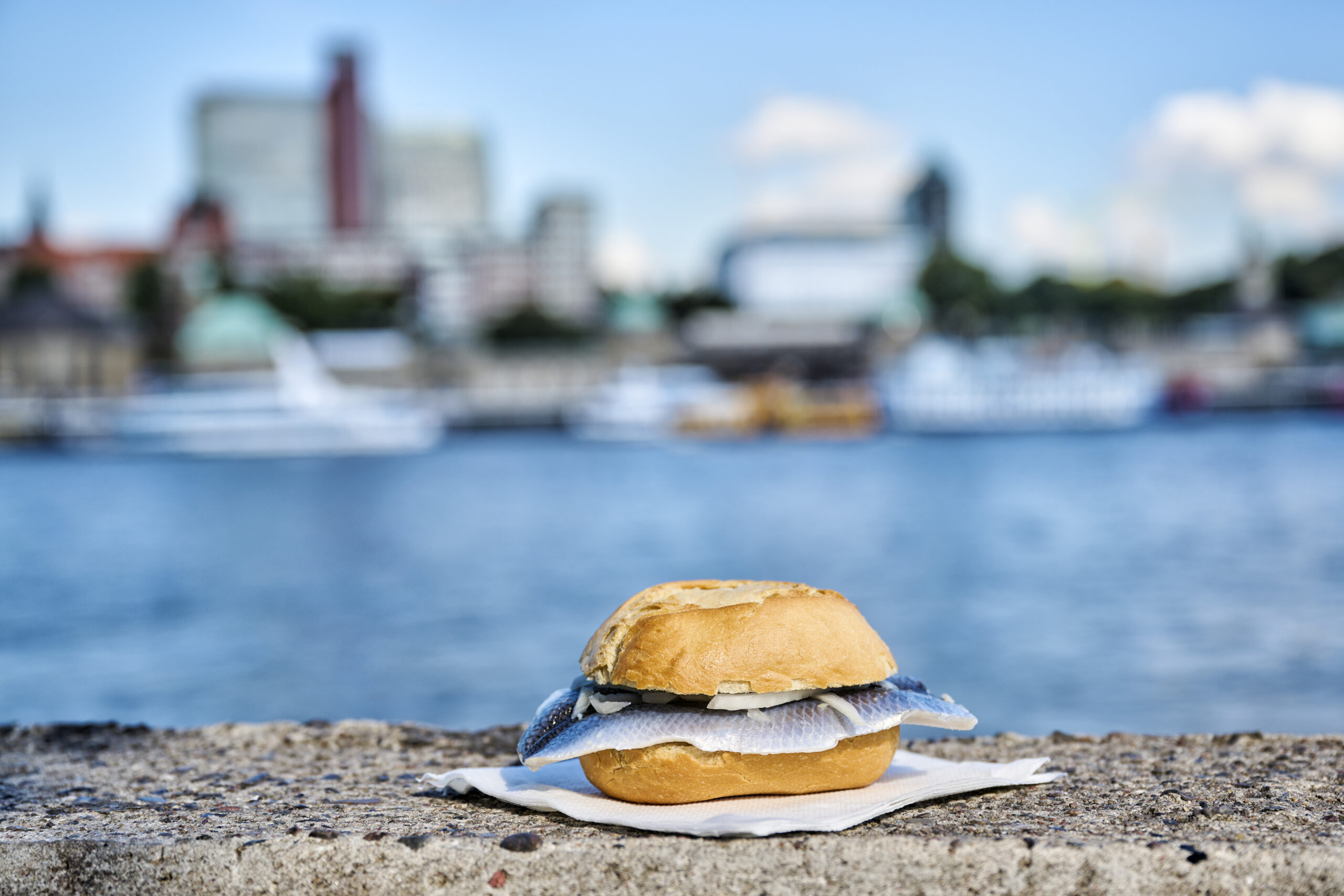 Ein Fischbrötchen liegt auf einer Mauer am Hafen in Hamburg