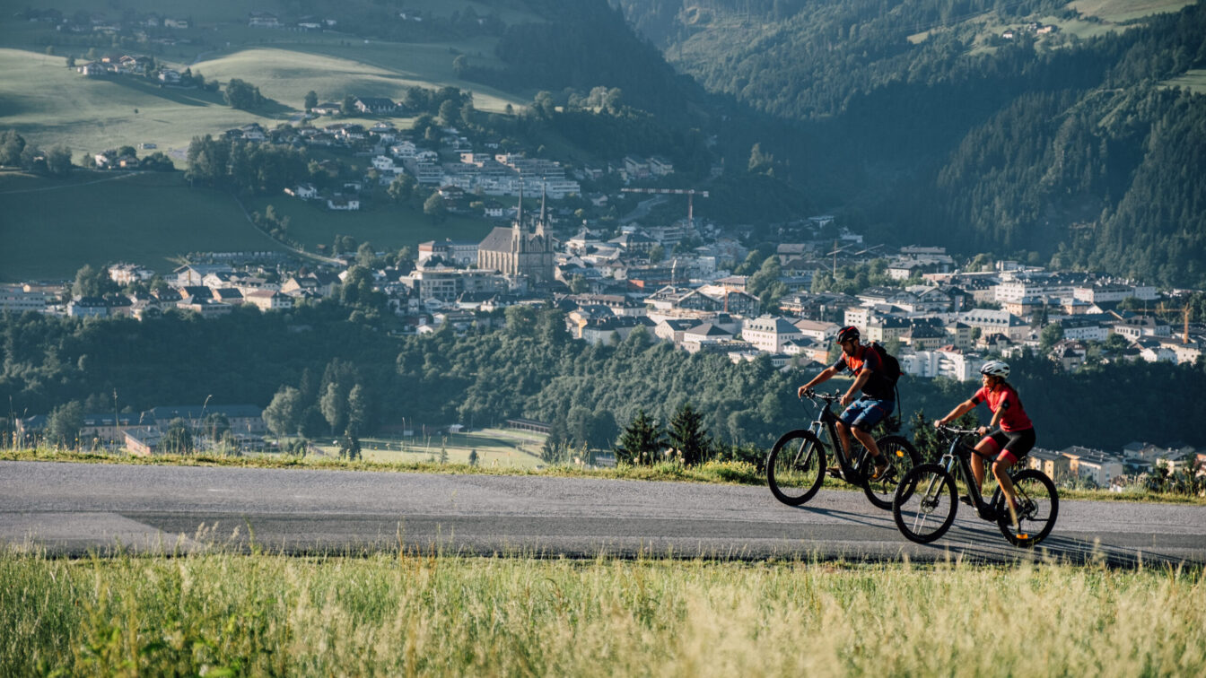 Zwei Radfahrer radeln an St. Johann in Salzburg vorbei