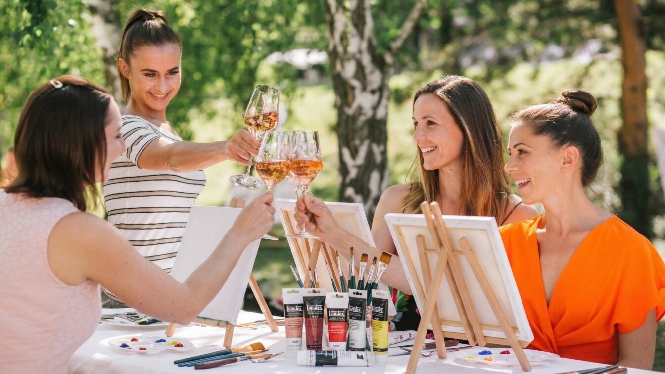 vier Frauen trinken Rosé im Garten und malen eigene Kunstwerke