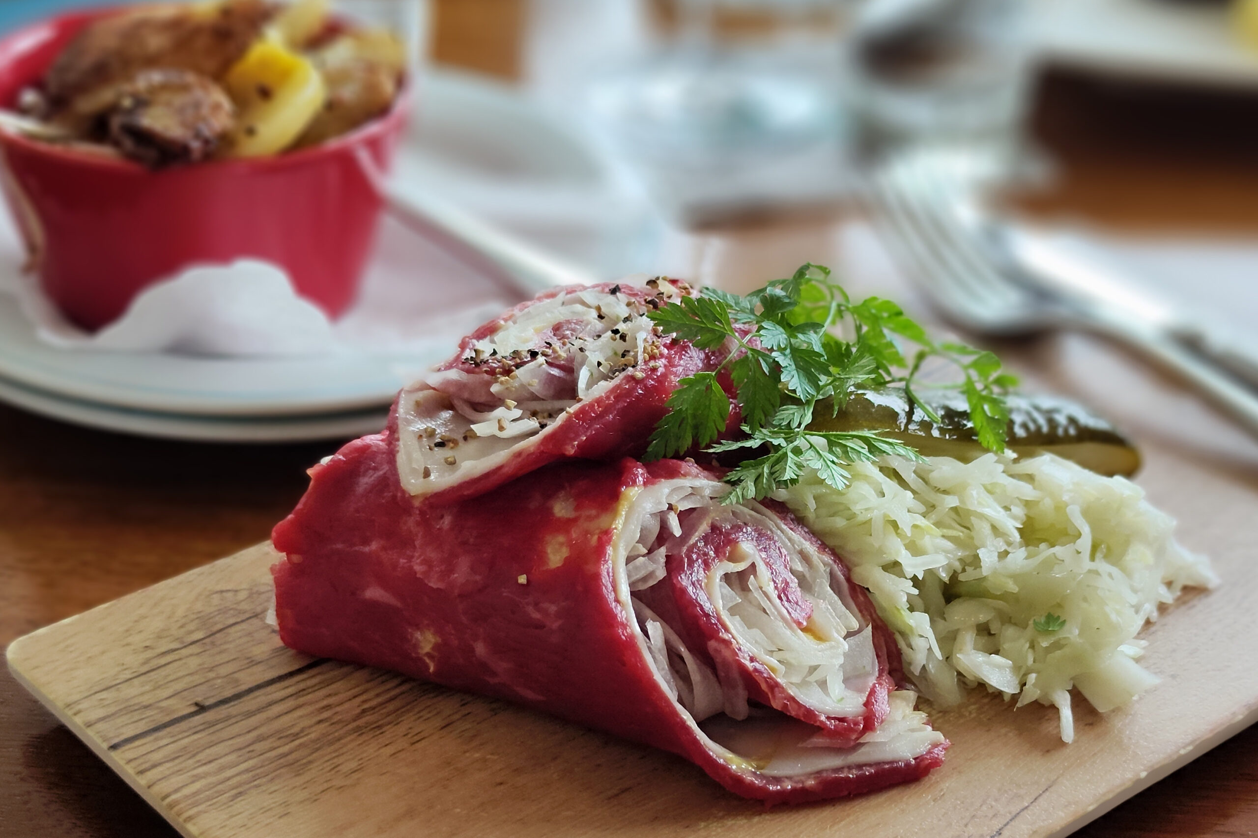 Kulinarischer Klassiker in der Stadt Celle: die Rohe Roulade ist zu sehen, eine rotfarbene Rolle aus Rindfleisch mit Speck, Zwiebeln, Senf und Gurke. Serviert auf einem Holzbrett. Traumhaft! 