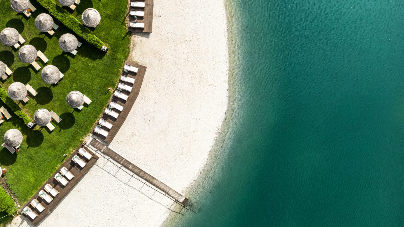 Strandam See der St. Martins Therme & Lodge mit Sonnenschirmen und Steg.