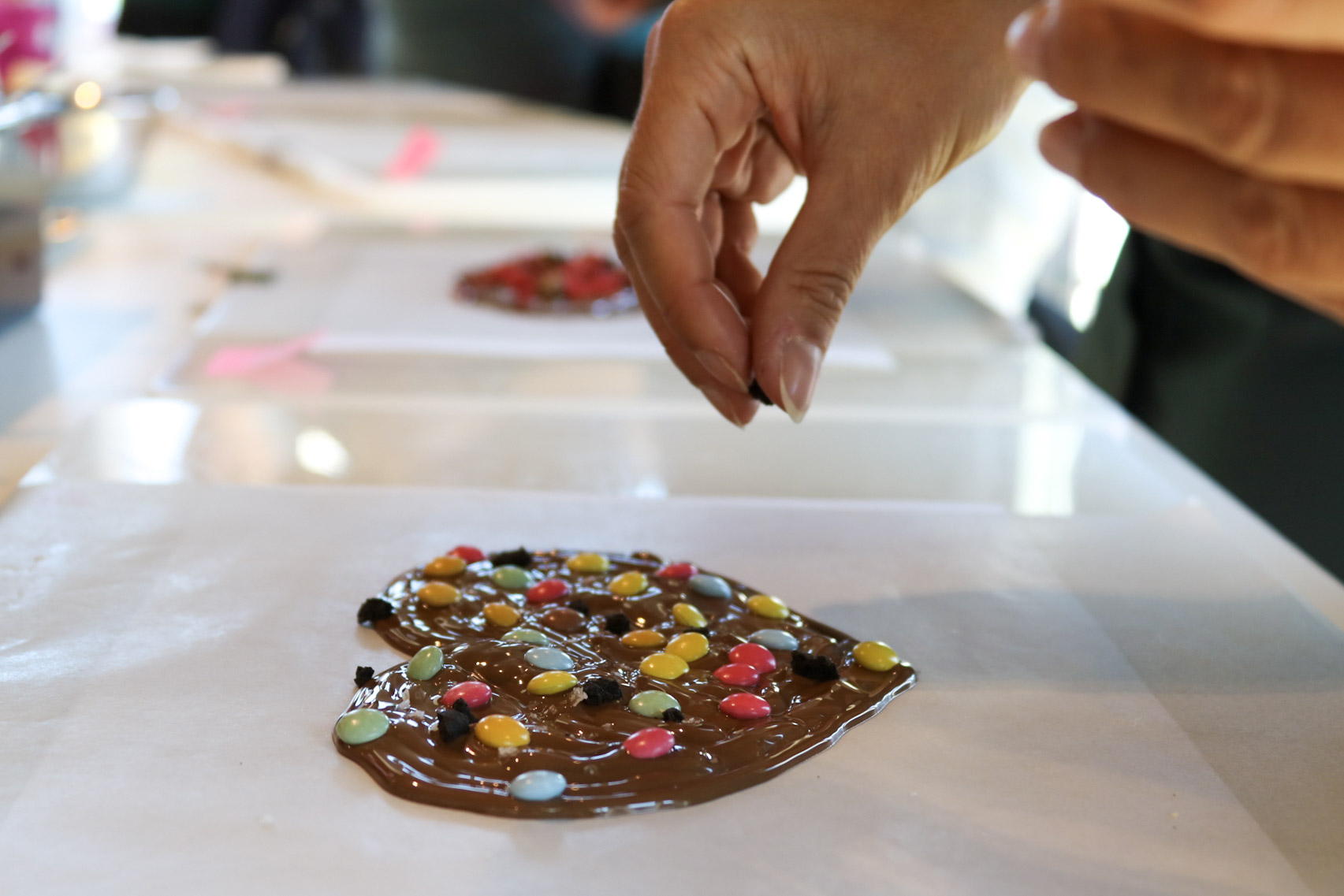 Jemand kreiert ein Schokoladenherz und verziert mit Smarties