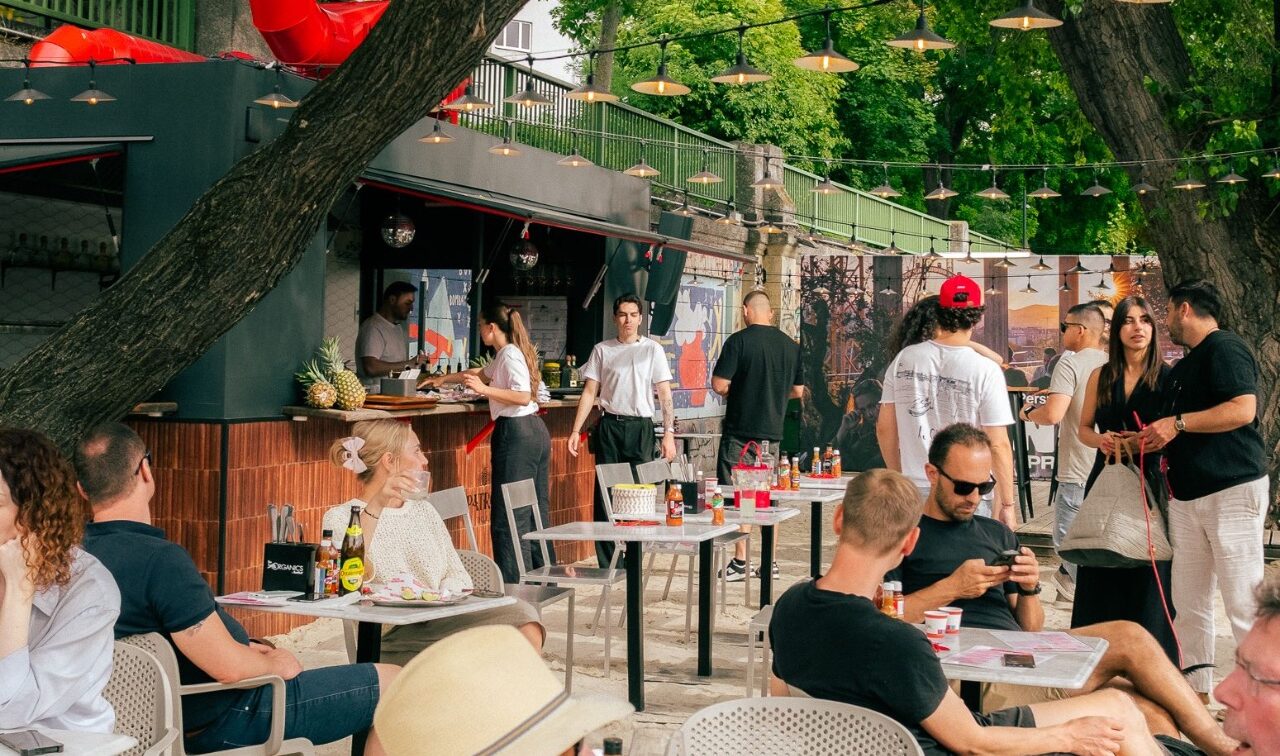 Menschen tummeln sich im Sand vor dem Lokal Casa Schuk am Donaukanal in Wien