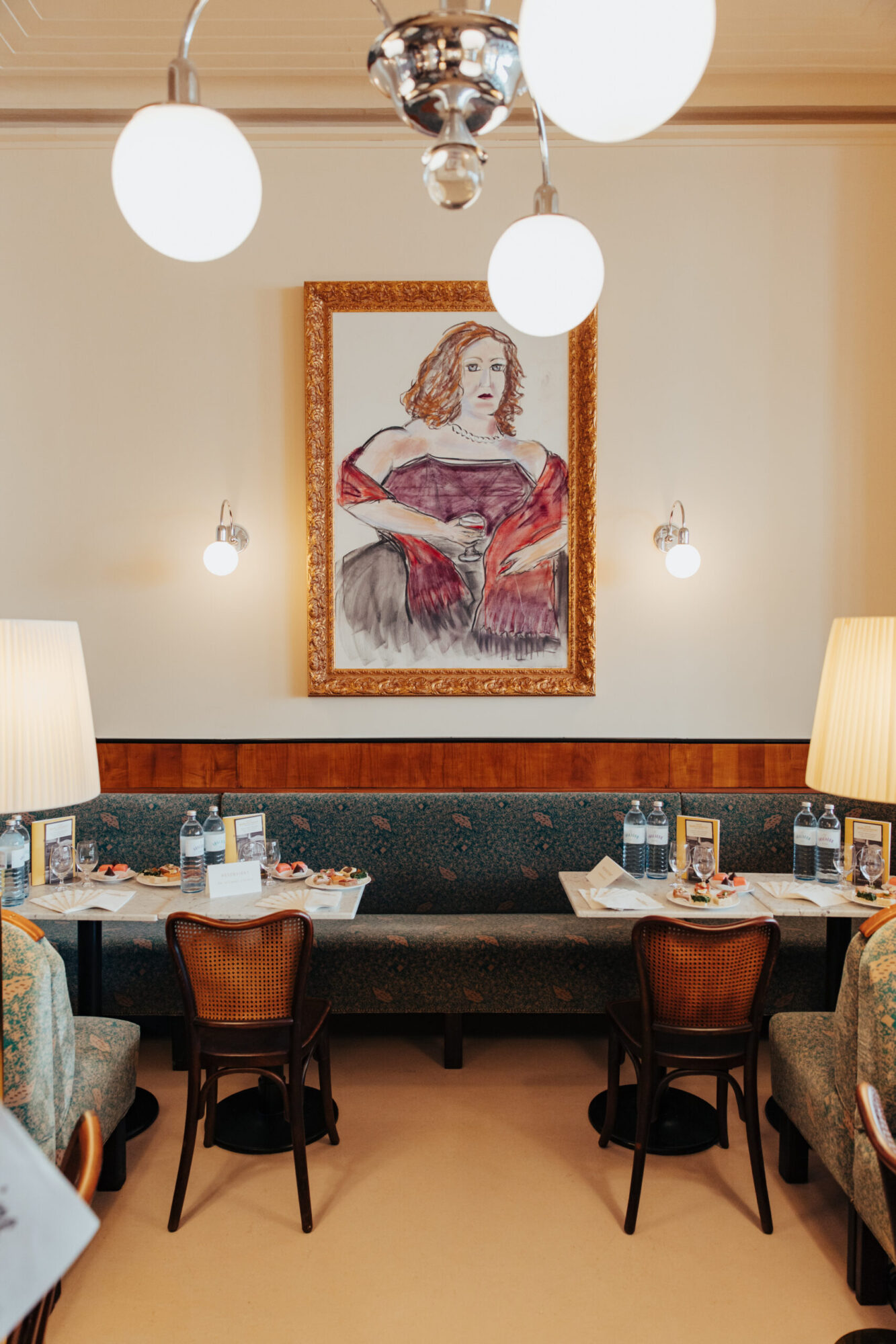 gedeckte Tische, eine Sitzbank und ein Gemälde an der Wand im Café Bräunerhof in Wien