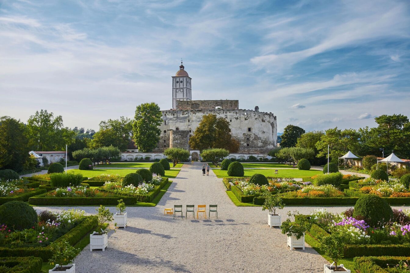 Im Hintergrund die Ruine der Schallaburg, im Vordergrund die Gärten mit grünen Wiesen und bunten Blumen