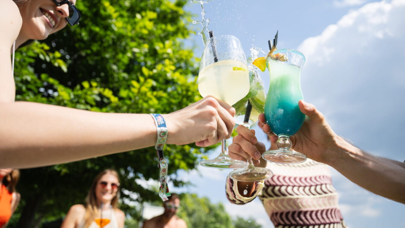 Menschen halten Cocktailgläser in die Luft und stoßen gemeinsam in der Therme Wien an