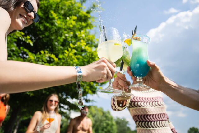 Menschen halten Cocktailgläser in die Luft und stoßen gemeinsam in der Therme Wien an