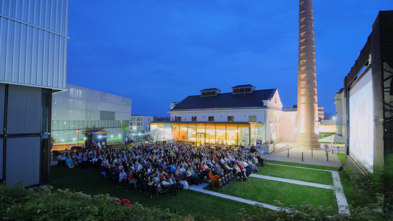 Menschen sitzen vor der Leinwand des abendlichen Sommerkinos beim Kesselhaus in Krems