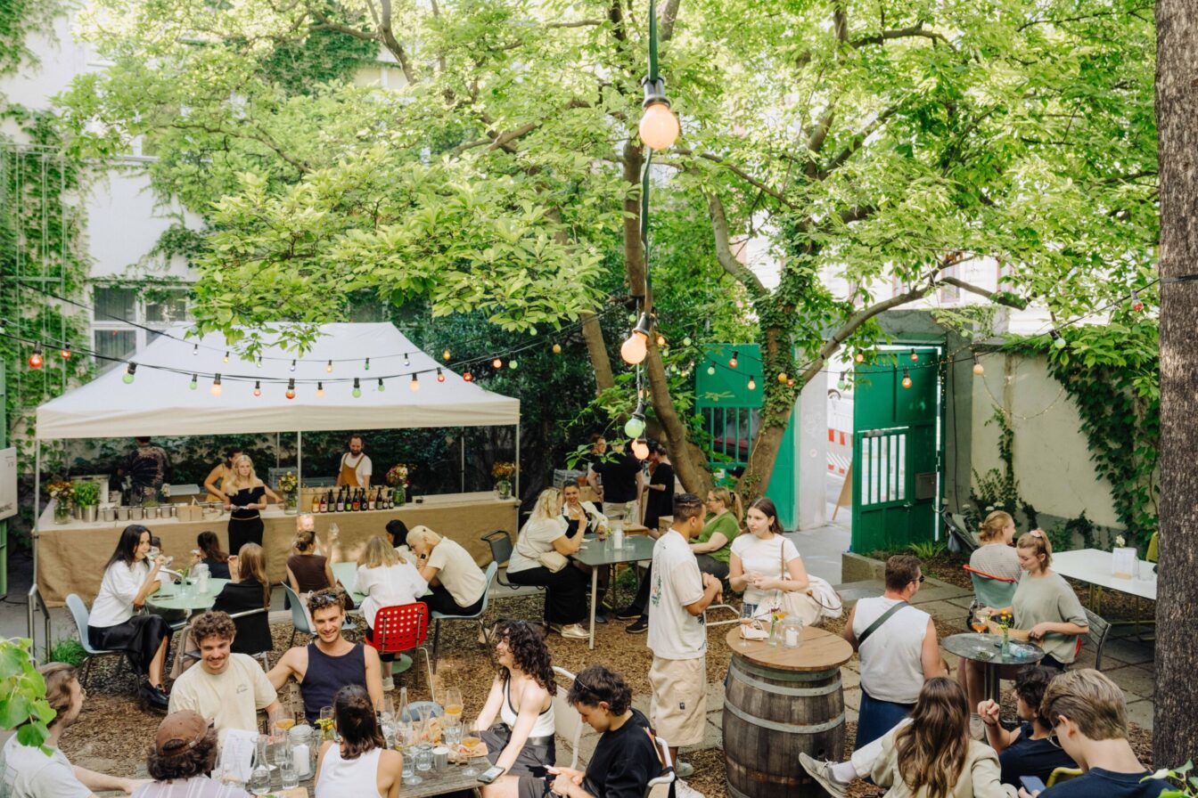 Menschen sitzen im Innenhof-Garten der Markterei Markthalle im 9. Bezirk in Wien