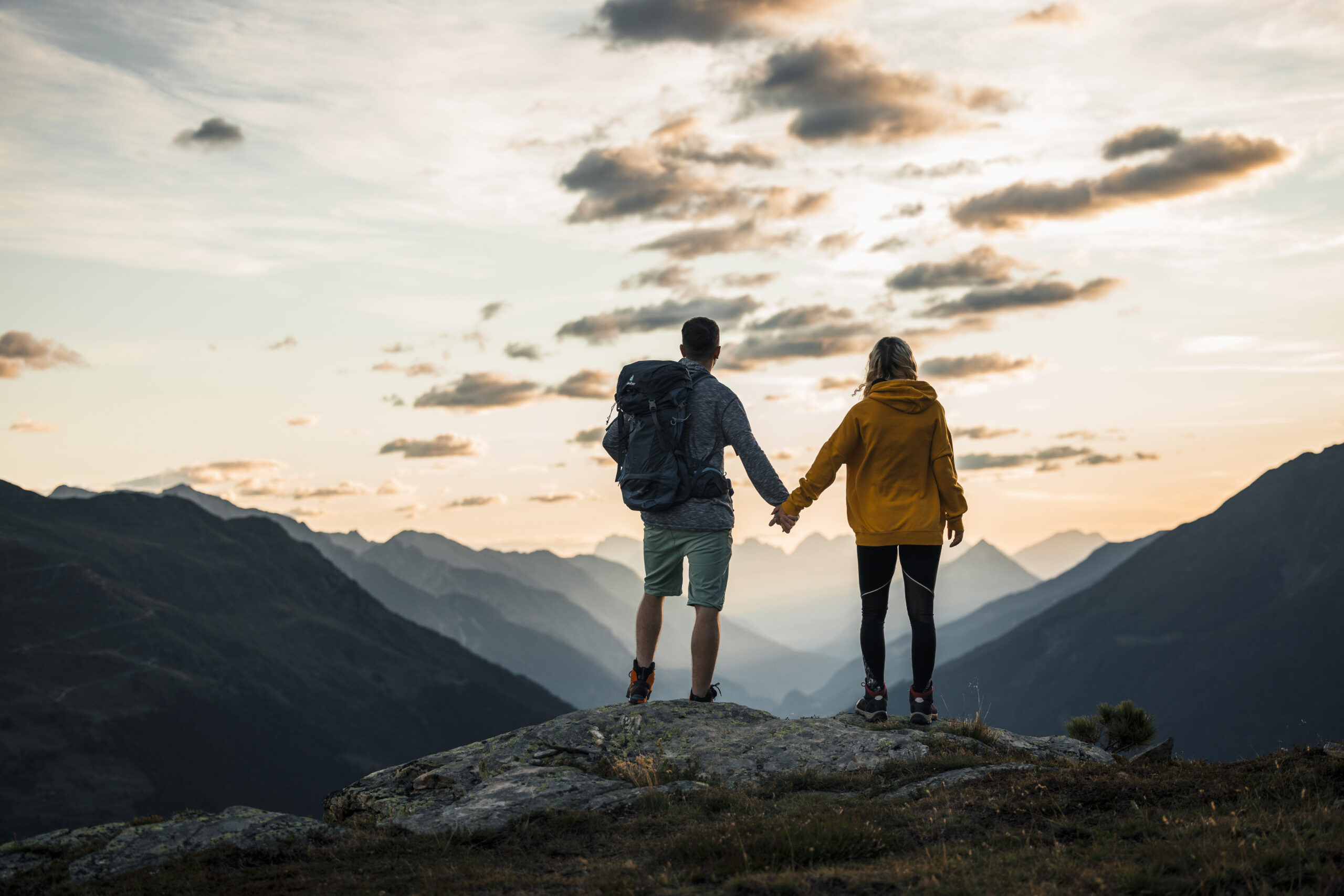 Zwei Personen geben sich die Hand am Berggipfel