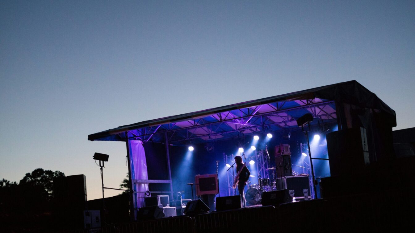 ein Mann steht vor dem Sonnenuntergang auf einer Bühne und gibt ein Konzert