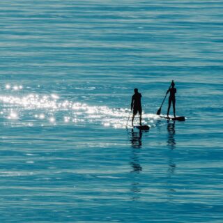 Stand-up-Paddler im Wasser bei Sonnenuntergang