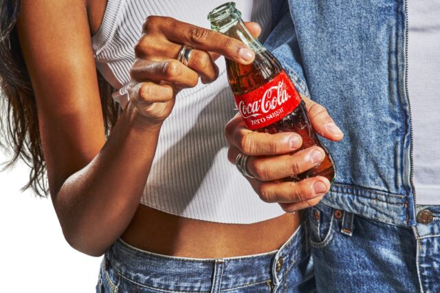 Frau und Mann halten eine Coca Cola Glasflasche