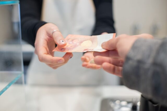 eine Kundschaft überreicht einer Servicekraft in einem Lokal einen 10-Euro-Schein