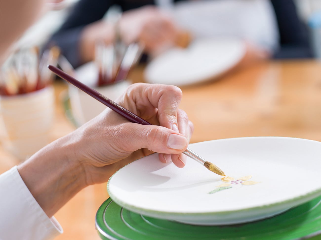 Ein Teller wird in der Gmundner Keramik Manufaktur bemalt, ein schöner Ausflug bei Schlechtwetter im Salzkammergut